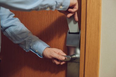 cropped shot of man inserting card into electronic lock in hotel clipart
