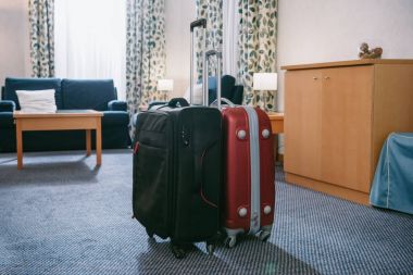 two suitcases standing in empty hotel room clipart