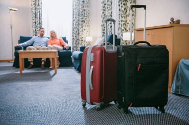 İki valiz ve Olgun çift otel odasında kanepede oturan yakından görmek