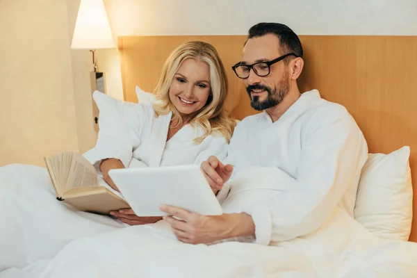 Feliz Casal Meia Idade Leitura Livro Usando Tablet Digital Enquanto — Fotografia de Stock