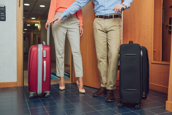 cropped shot of mature couple with suitcases entering into hotel room