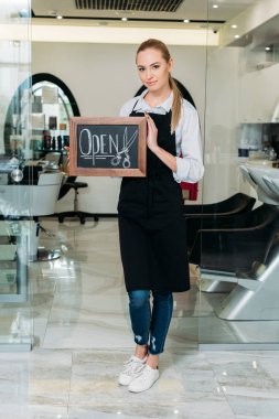 Oturum açıkken ayakta ve kameraya bakarak salon sarışın sahibi