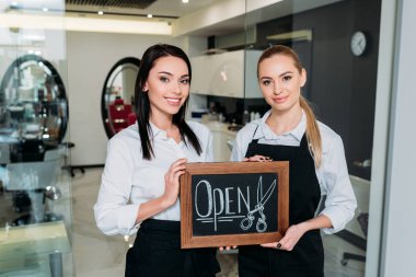 beautiful hairdressers standing with signboard open clipart