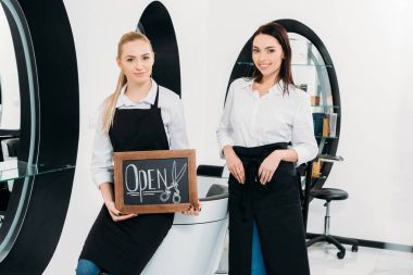 two hairdressers with signboard open at hair salon clipart