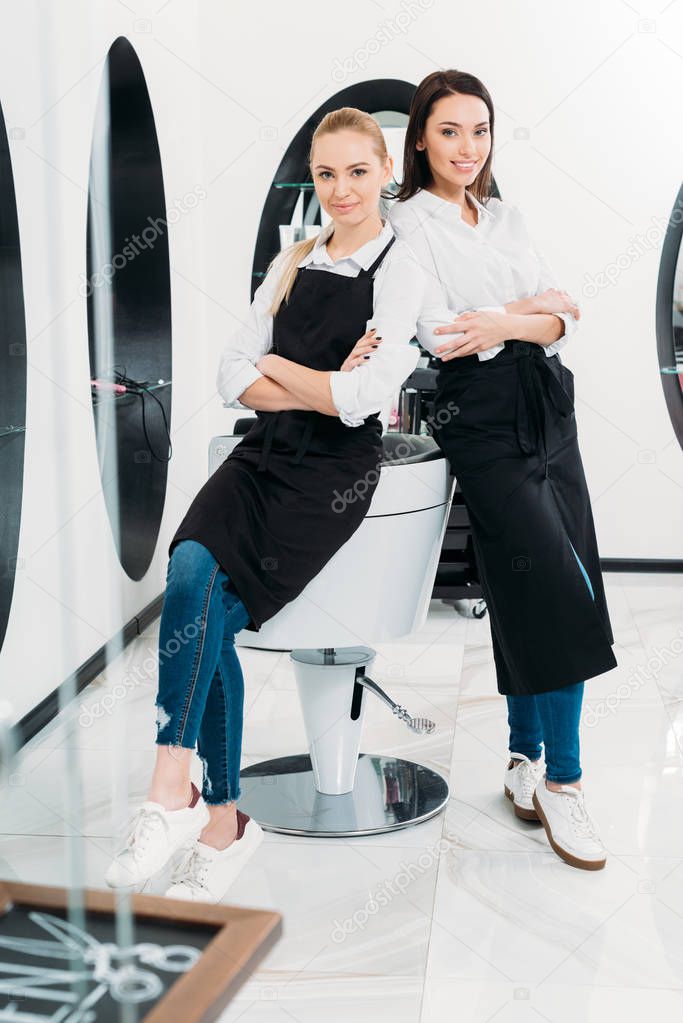two hairdressers leaning on hairdresser chair at salon