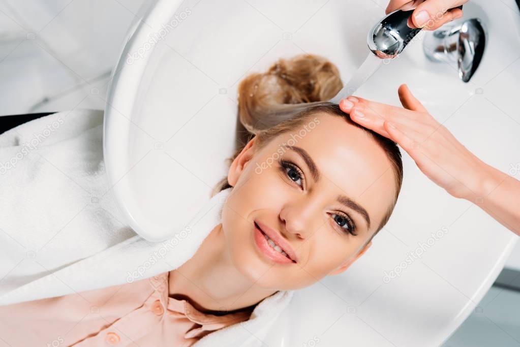 top view of hairdresser washing hair for customer at salon