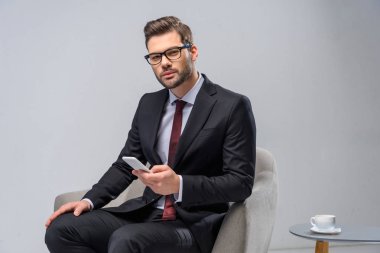 koltukta oturan ve smartphone tutan işadamı
