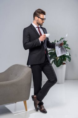 yakışıklı işadamı kahve tutarak ve gazete okuma