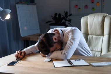 tired businessman sleeping at working table clipart