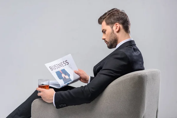 Geschäftsmann Liest Zeitung Und Hält Glas Whiskey Der Hand — Stockfoto