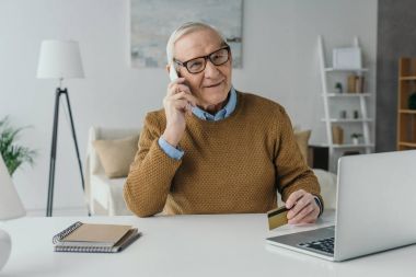 Yaşlı gülümseyen adam ofisinde çalışan ve telefon görüşmesi