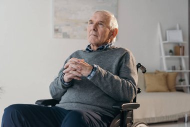 Boş odada tekerlekli sandalyede üst düzey düşünceli adam