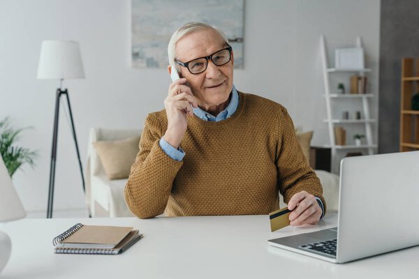 Elder smiling man working in office and making phone call