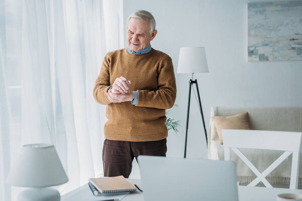 Senior man working in office and checking his heart rate