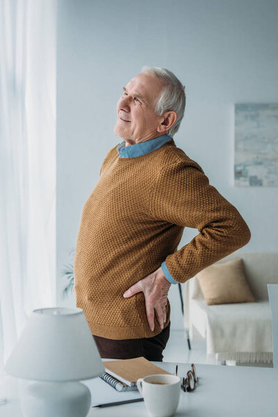 Senior man working in office suffering from back pain