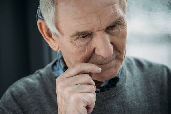 Старший мужчина с грустным выражением лица плачет
 