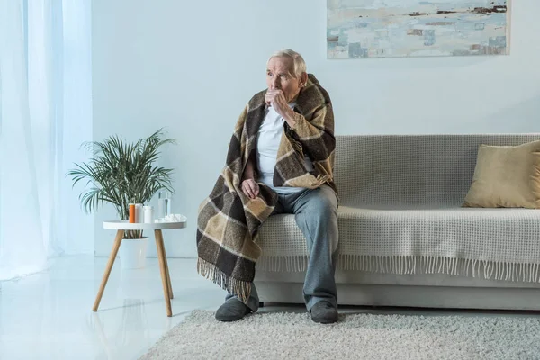 Больной Пожилой Человек Клетчатом Кашле Сидя Диване Комнате Лекарствами Столе — стоковое фото