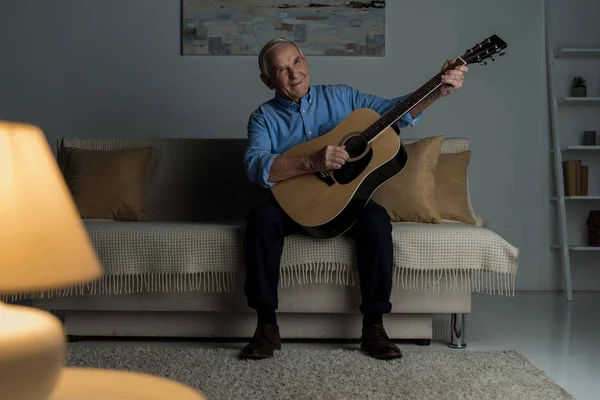 Senior Feliz Homem Toca Guitarra Acústica Enquanto Sentado Sofá Quarto — Fotografia de Stock