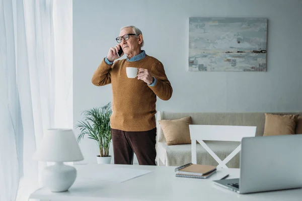 オフィスで働く電話をかける コーヒー カップを持つシニア自信を持って男 ロイヤリティフリーのストック画像