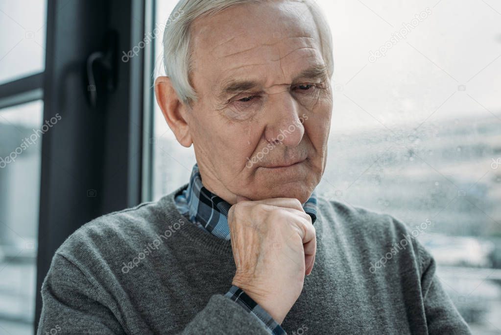 Senior thoughtful man with sad expression cries 