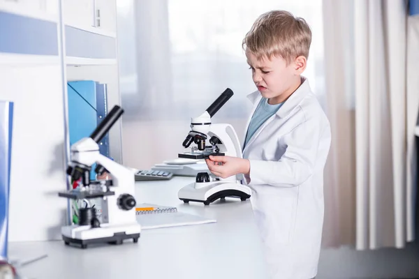Маленький хлопчик використовує мікроскоп — стокове фото