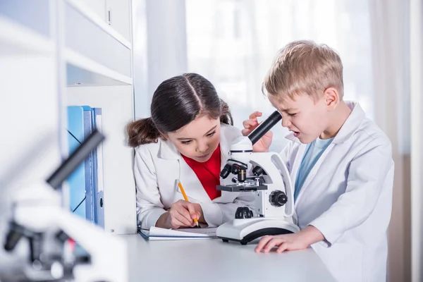 Niños usando microscopio - foto de stock