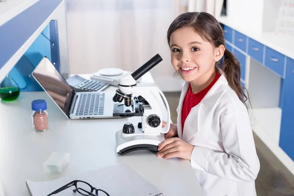 Chica usando microscopio - foto de stock