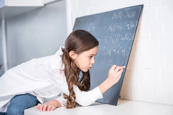 Kleines Mädchen schreibt chemische Formel — Stockfoto