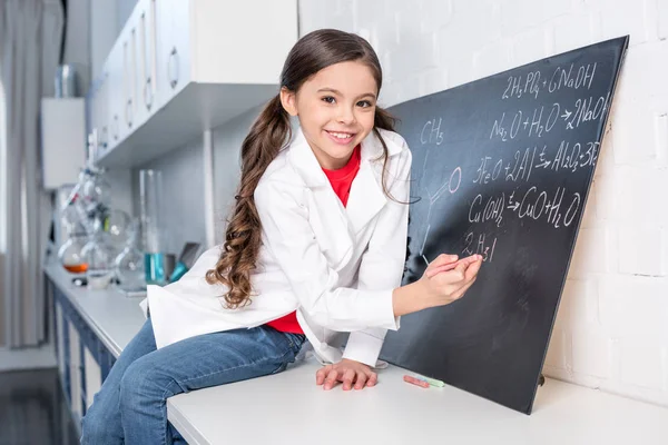 Niña escribiendo fórmula química - foto de stock