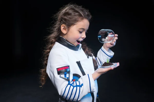 Girl astronaut holding plant — Stock Photo