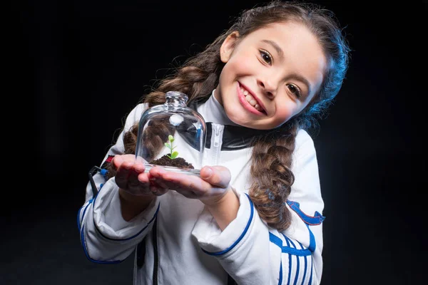 Girl astronaut holding plant — Stock Photo