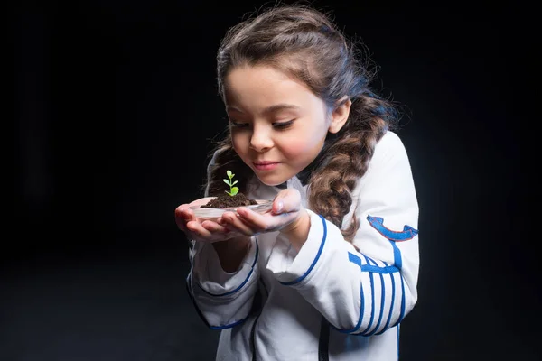 Girl astronaut holding plant — Stock Photo