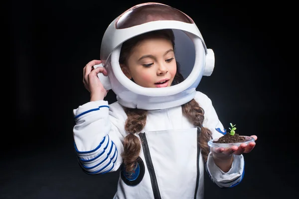 Girl astronaut holding plant — Stock Photo