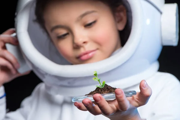 Girl astronaut holding plant — Stock Photo