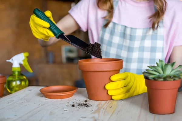 Woman heaping ground in flowerpot — Stock Photo