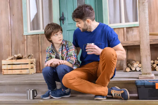 Hombre y niño sentado en el porche - foto de stock