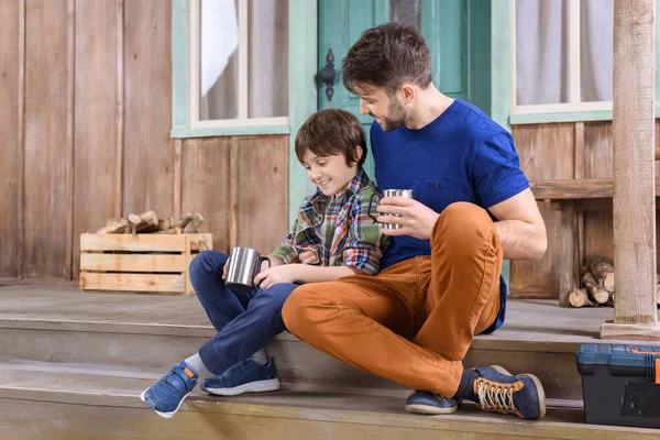Hombre y niño sentado en el porche - foto de stock