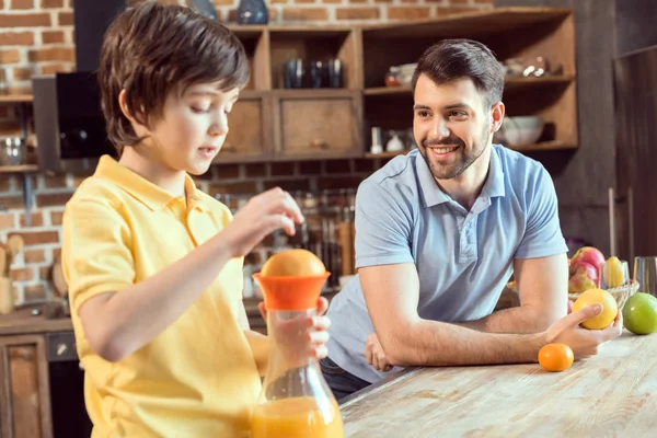 Padre e hijo exprimiendo jugo - foto de stock