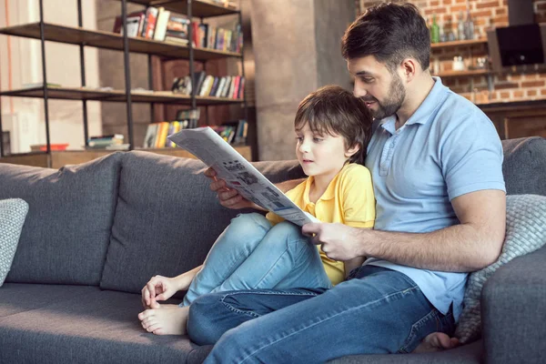 Батько і син читають газету — стокове фото