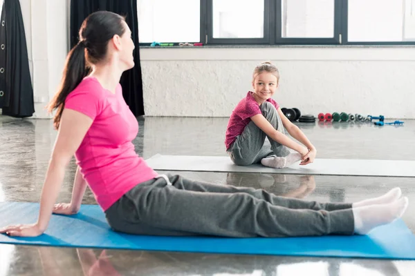 Madre e hija sentadas en colchonetas de yoga - foto de stock