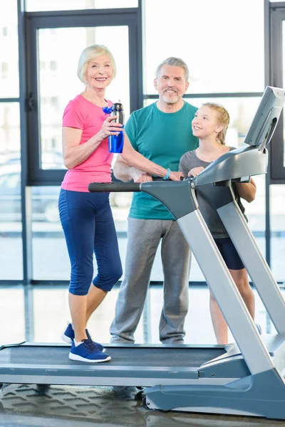 Senior couple and girl on treadmill — Stock Photo