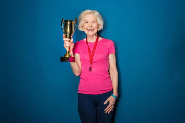 Senior sportswoman holding trophy — Stock Photo