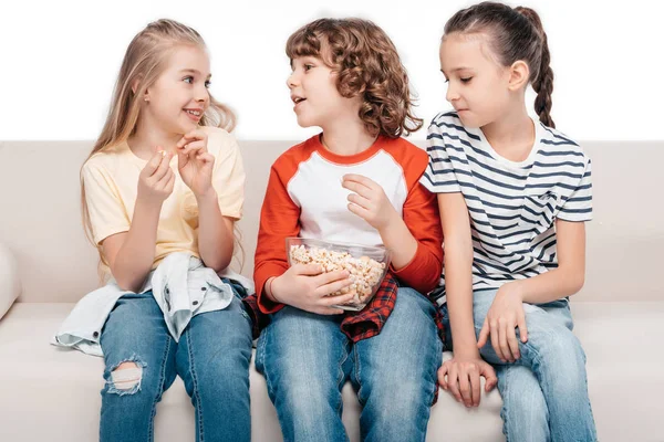 Enfants mignons sur le canapé avec du pop-corn — Photo de stock