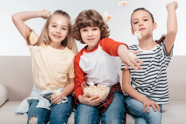 Lindos niños en el sofá con palomitas de maíz - foto de stock