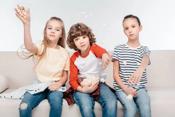 Cute children on couch with popcorn — Stock Photo