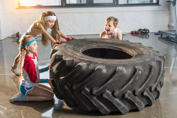 Entrenamiento de niños con neumático en el gimnasio - foto de stock