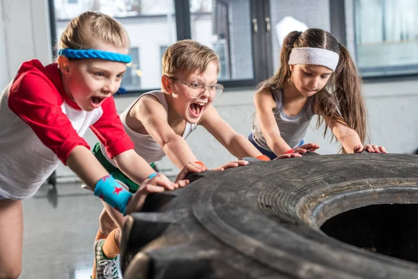 Entrenamiento de niños con neumático en el gimnasio - foto de stock
