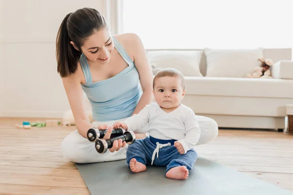 Mujer con bebé usando mancuernas - foto de stock