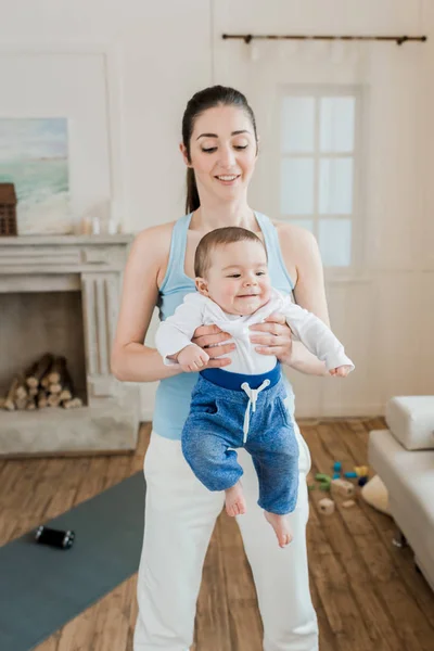 Femme portant bébé enfant sur les bras — Photo de stock