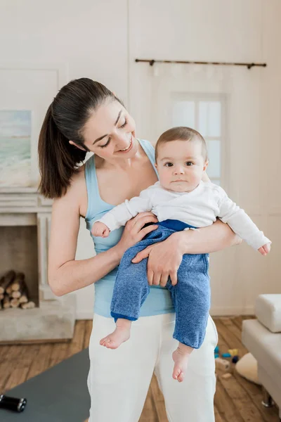 Femme portant bébé enfant sur les bras — Photo de stock